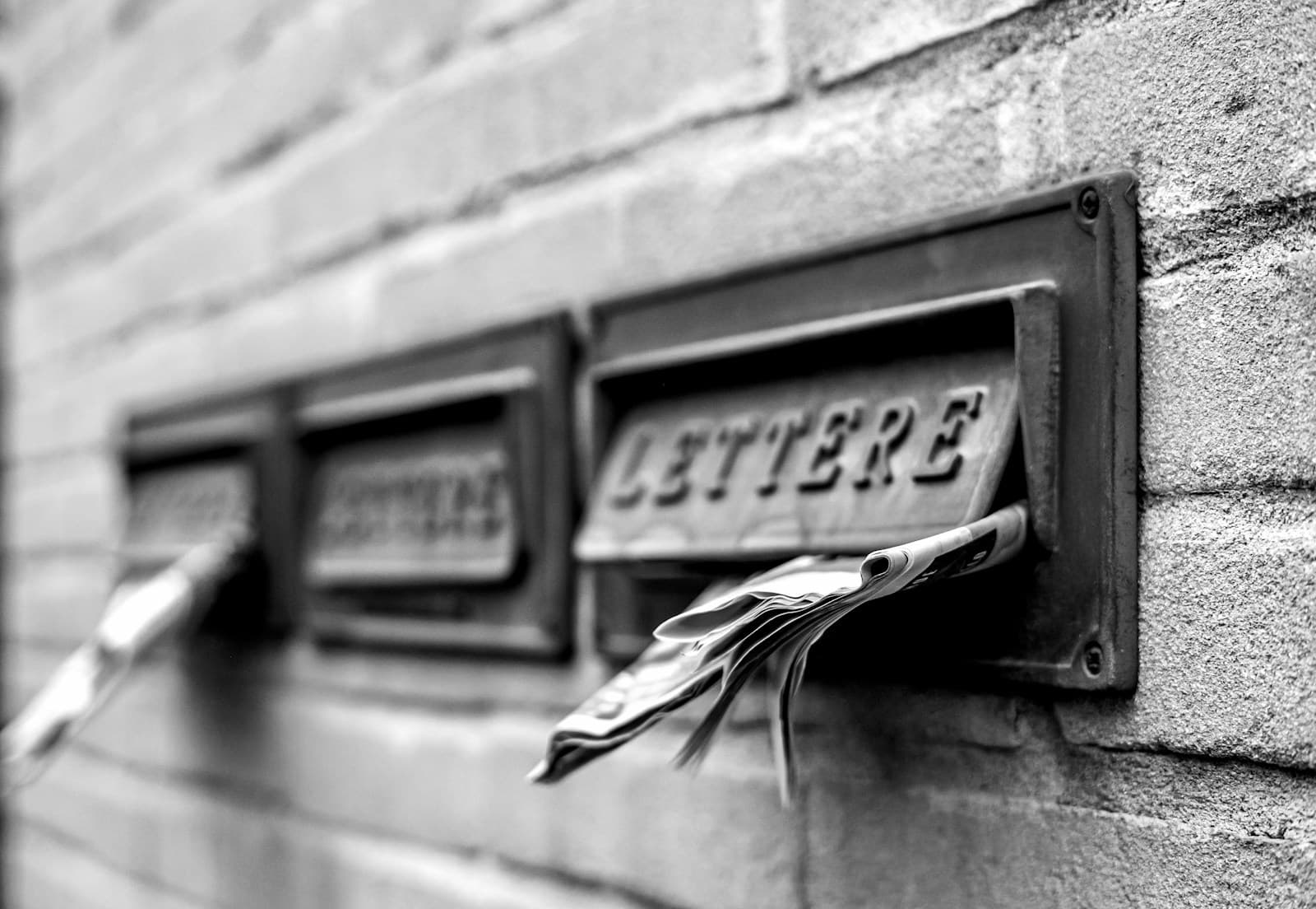 Three metal letterboxes mounted on a brick wall